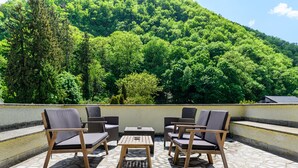 Un área de estar al aire libre con una mesa y sillas, con vistas a una ladera verde exuberante.