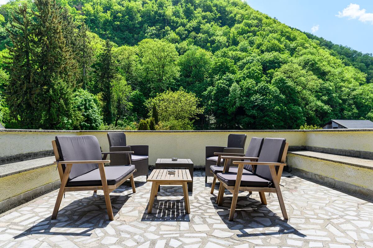 Un área de estar al aire libre con una mesa y sillas, con vistas a una ladera verde exuberante.