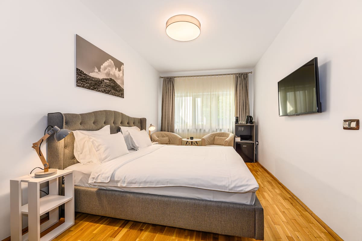 Habitación de hotel moderna con una cama grande, televisión de pantalla plana, escritorio con lámpara y una silla.