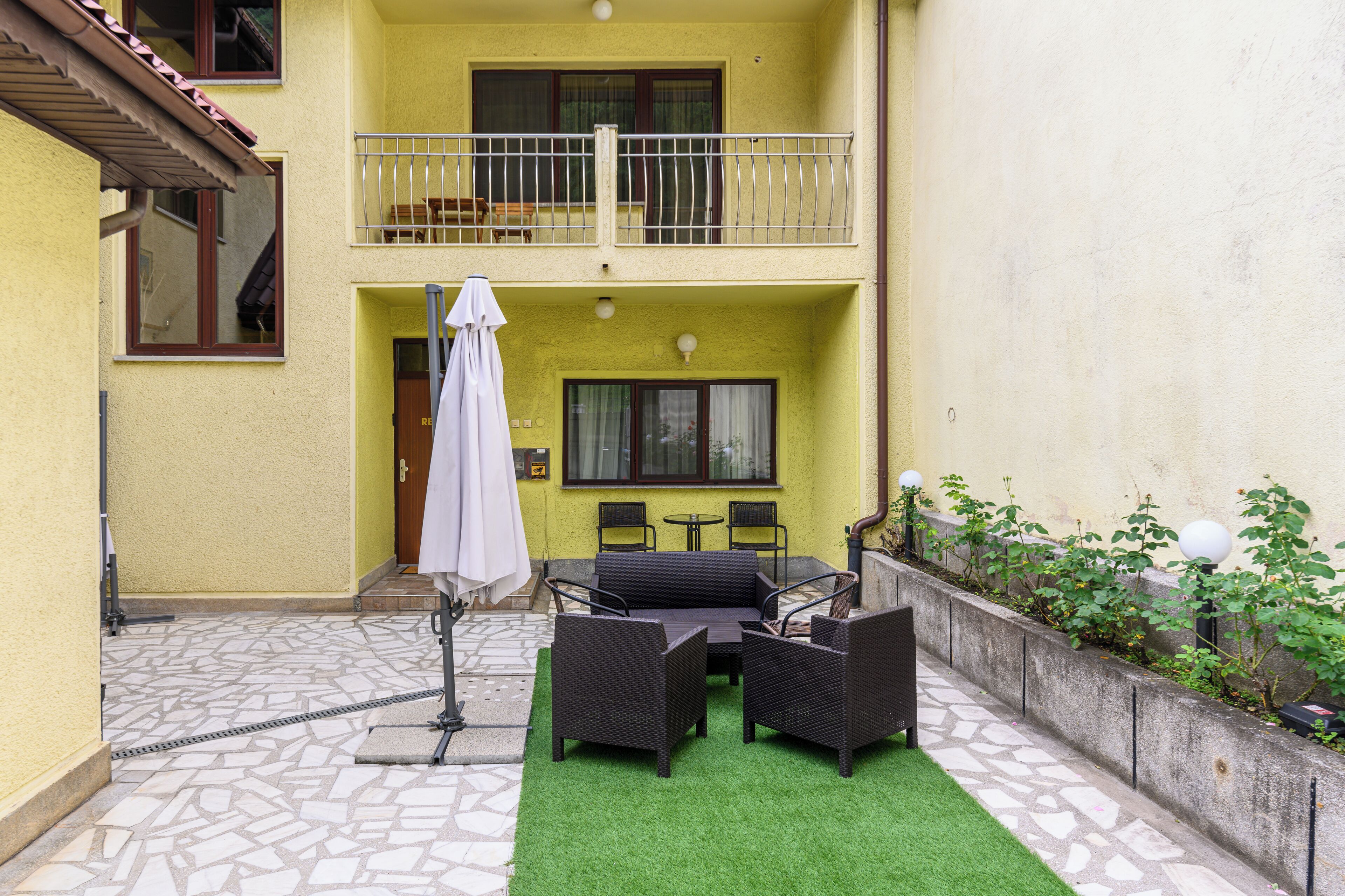 Une cour avec un ensemble de meubles de salon, une table et un parasol.
