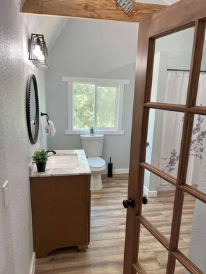 A bathroom with a toilet, sink, and window.
