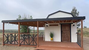A small building with a 'WELCOME' sign, a wooden door, and a covered outdoor area with tables and chairs. - Modern wine country barn house (Temecula)