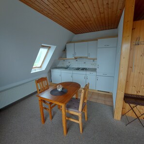 A compact kitchen with white cabinets, a dining table with chairs, and a small window.