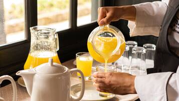Une personne verse du jus d’orange d’une carafe dans un verre.