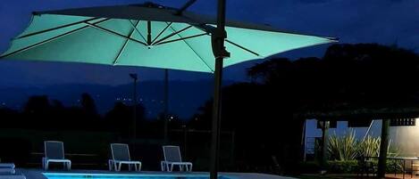 Una piscina con un paraguas grande y sillas de descanso.