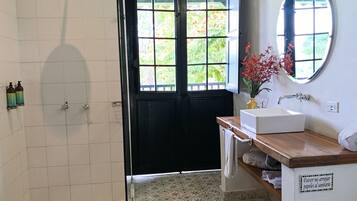 Een badkamer met een douche, wastafel, spiegel en vloertegels met een patroon.