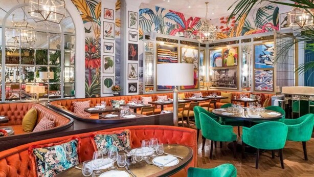A restaurant with round tables, orange cushioned booths, and green chairs. - Gorgeous 2-bed Apartment With Patio (Brighton)