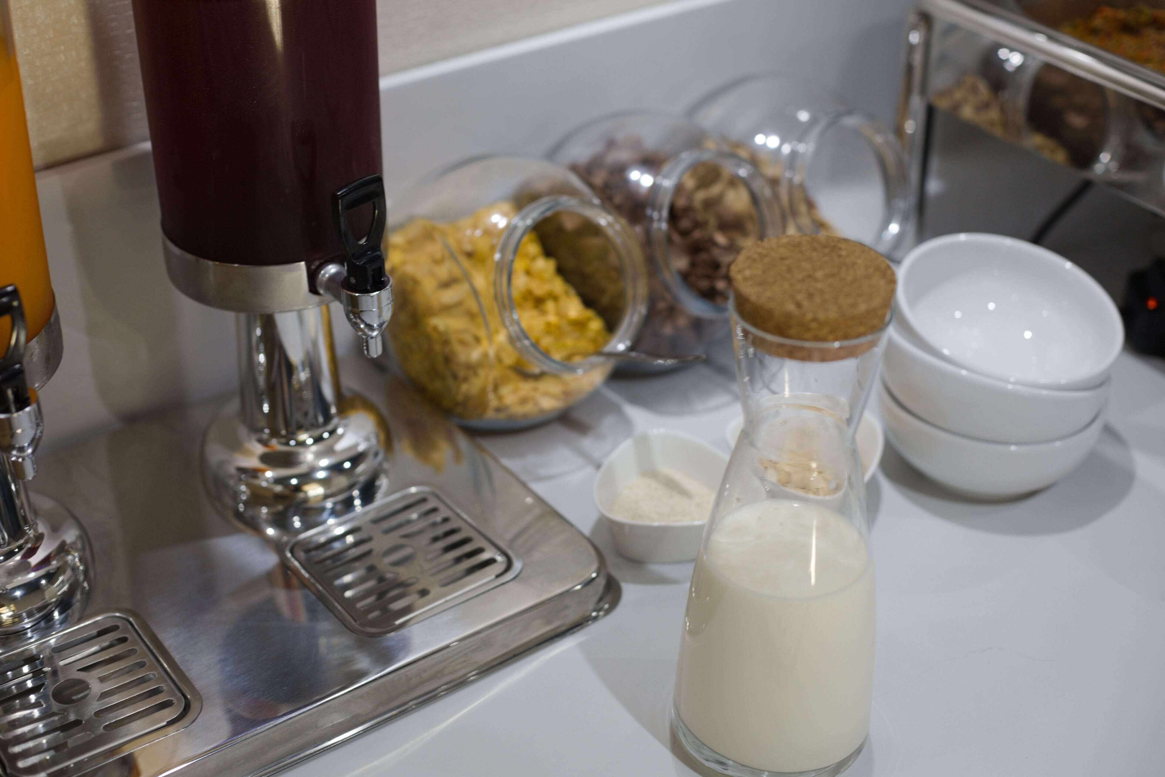 A coffee machine with milk and sugar dispensers, a coffee grinder, and various coffee pods.