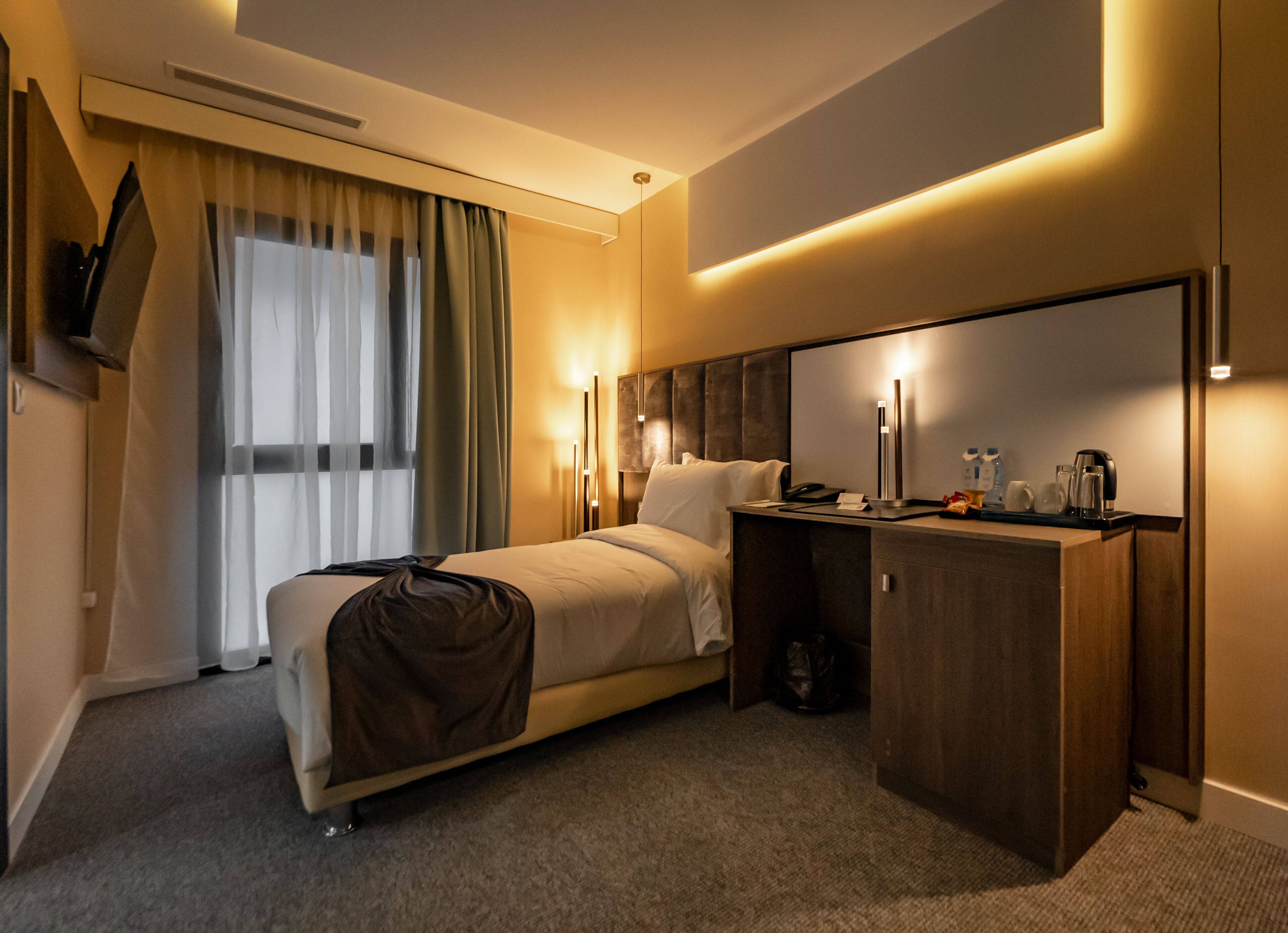 Una habitación de hotel moderna con cama, mesita de noche y escritorio con silla.
