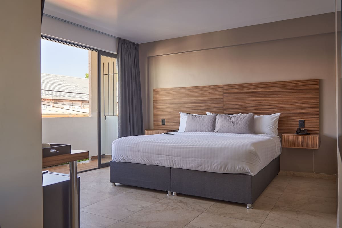 A modern bedroom with a large bed, a bedside table, and a view of the outside.