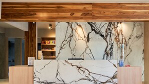 Una recepción con un muro de fondo de mármol, paneles de madera arriba y un estante con diversos objetos.