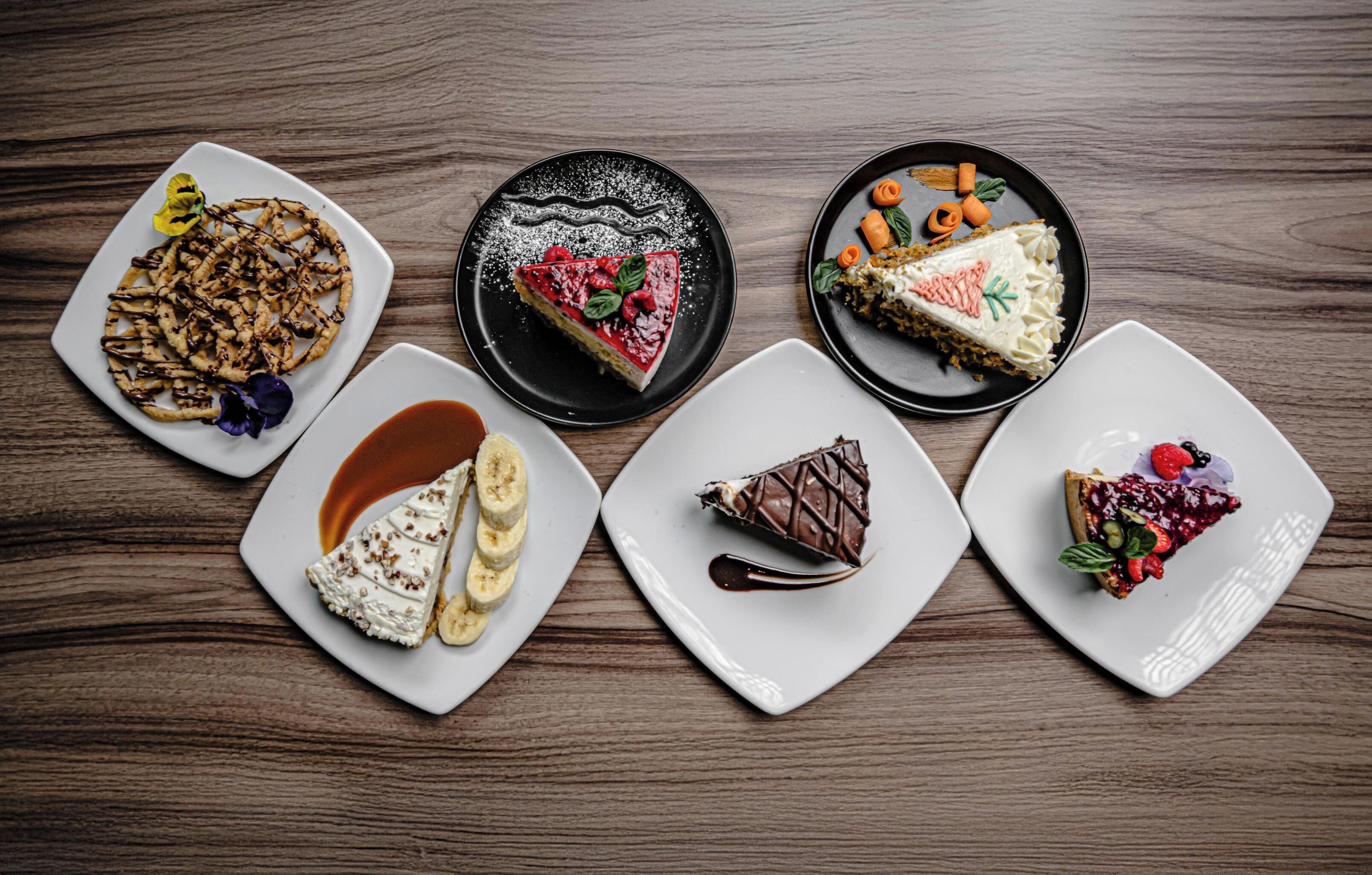 A variety of desserts on white plates with a wooden table background.