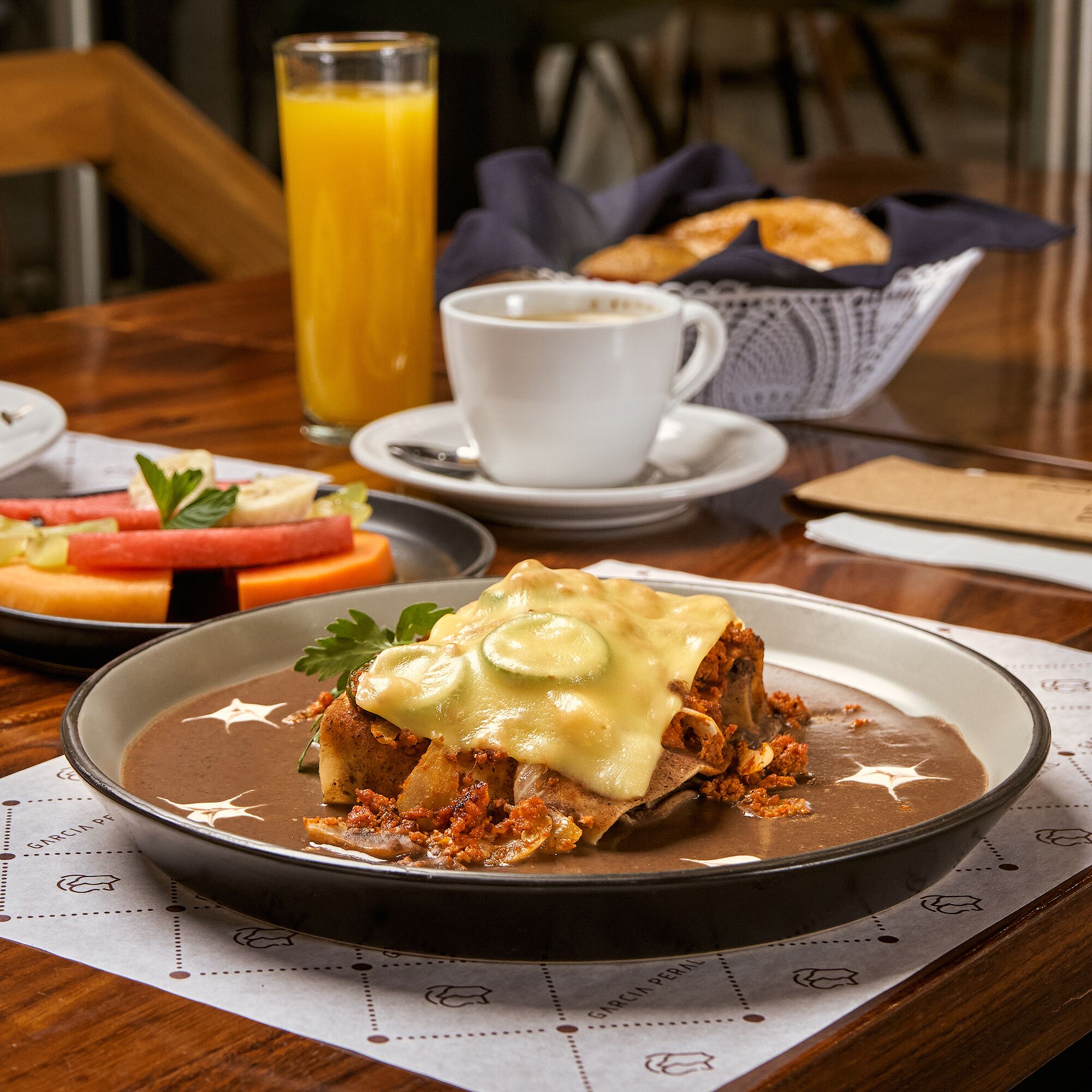 A breakfast setting with a plate of food, a cup of coffee, and a glass of orange juice on a wooden table.