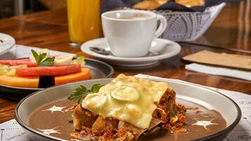 A breakfast setting with a plate of food, a cup of coffee, and a glass of orange juice on a wooden table.