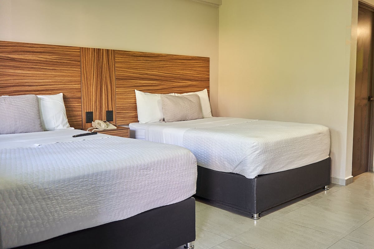 Two twin beds with white bedding and dark headboards in a hotel room.