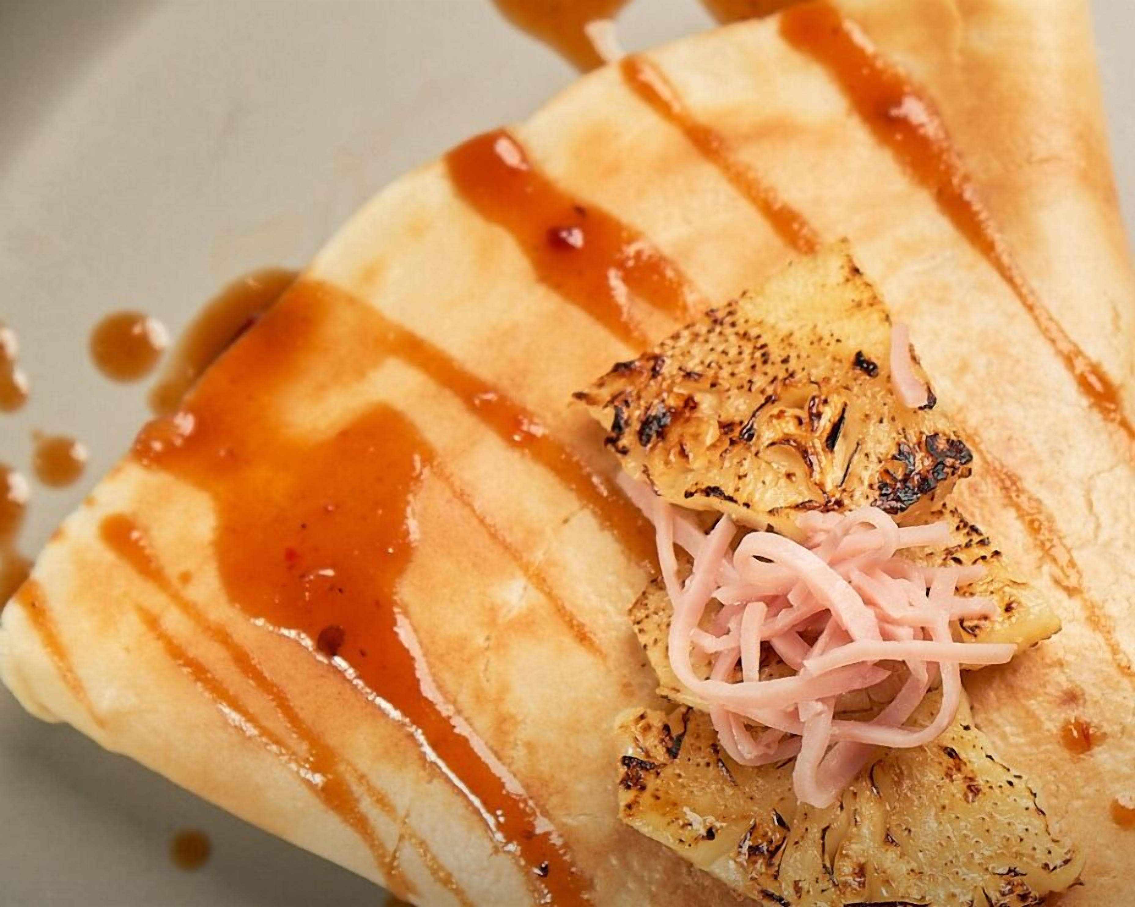 A dish with grilled chicken, pickled onions, and a drizzle of sauce on a plate.