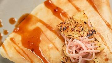A dish with grilled chicken, pickled onions, and a drizzle of sauce on a plate.