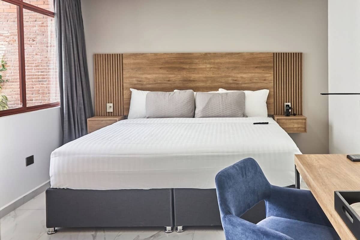 A modern hotel room with a large bed, a desk, and a chair.