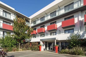 A modern building with a flat roof, multiple balconies, and a parking area. - Best Western Les Aureliades (Trignac)