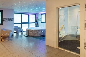 A modern spa area with a hot tub, seating, and a glass-enclosed shower. - Best Western Les Aureliades (Trignac)