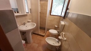 A compact bathroom with a sink, toilet, and shower.