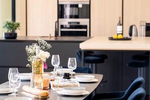 A modern dining area with a long table set for a meal, including plates, glasses, and a bottle of wine. - Villa Monégasque, elegance & exclusive seaside getaway (Sérignan)