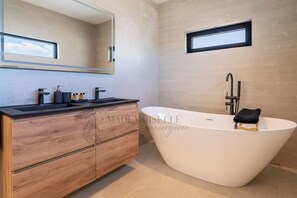 Une salle de bain moderne avec une baignoire sur pieds, un meuble-lavabo en bois et un grand miroir.