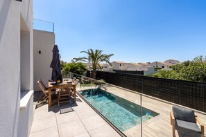 A rooftop pool area with a glass barrier, a wooden table with chairs, and a covered umbrella. - Villa Monégasque, elegance & exclusive seaside getaway (Sérignan)