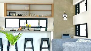 A modern kitchen with a central island, bar stools, and a hanging light fixture. - Into The Sea - 5 mins from the Beach (Albion)