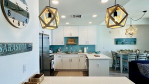 Una cocina moderna con una isla central, luces colgantes y un reloj en la pared.