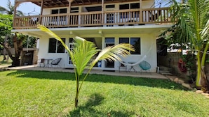 A two-story house with a balcony, a hammock, and a small garden.