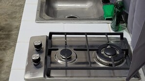 A kitchen with a gas stove, a sink, and a blender.