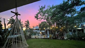 A garden with a hammock, a thatched-roof structure, and string lights.