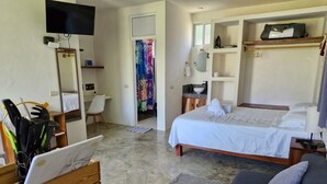 A hotel room with a bed, a desk, a chair, a TV, and a bathroom. - Mangal Suites Malinche (Sonora Brisas de Zicatela)