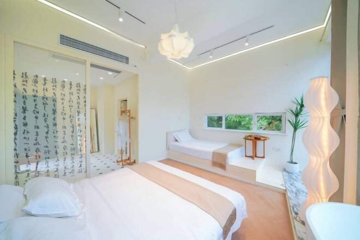 Un dormitorio moderno con una cama grande, mesitas de noche, un ventanal con vistas y una lámpara original.
