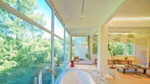 Un baño moderno con una bañera grande, una zona de ducha y un área de descanso con vistas al bosque.