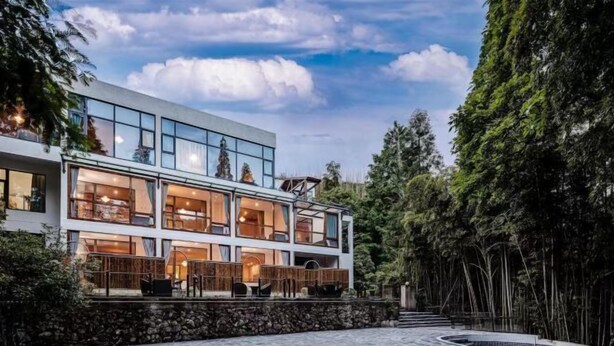 Un moderno edificio de dos pisos con grandes ventanales, piscina y pared de piedra.