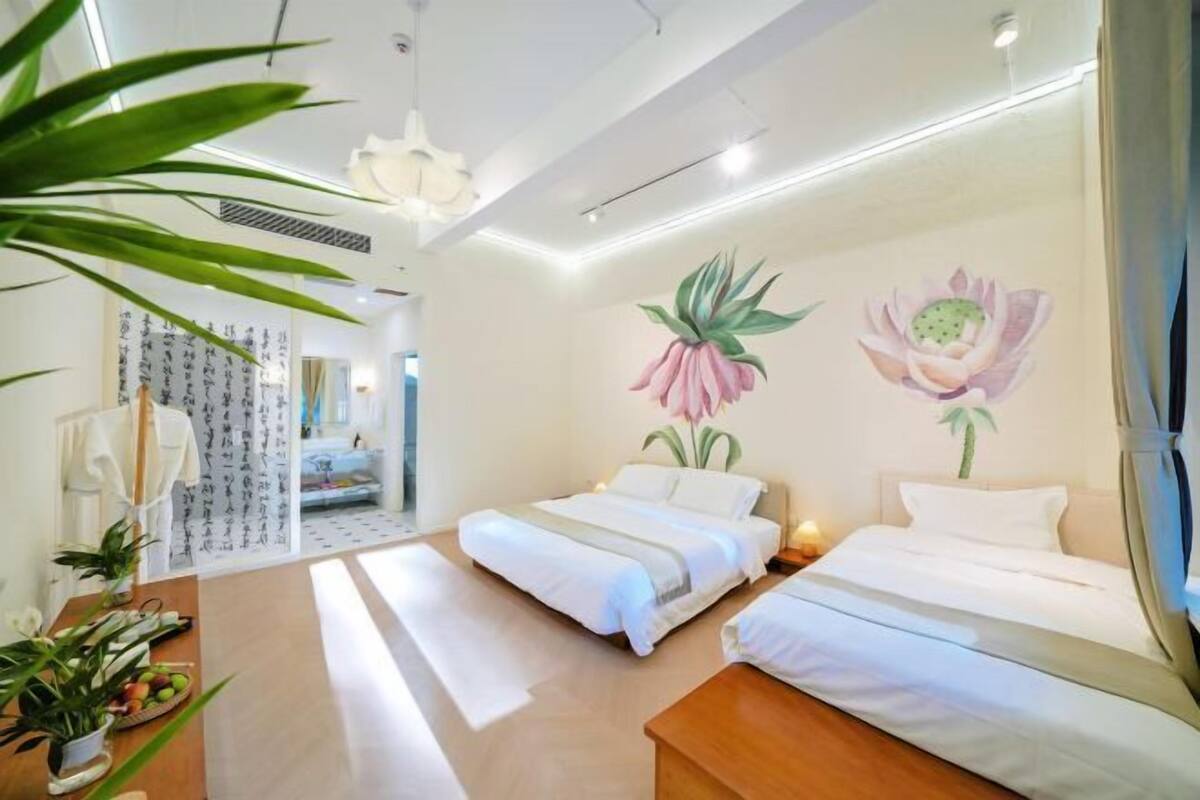 Habitación de hotel con dos camas, un ventanal grande y una pared decorada con motivos florales.