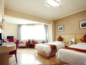 Habitació d'hotel amb dos llits, una taula amb un ordinador, una cadira i una finestra amb cortines.