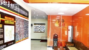 A restaurant with a tiled floor, a wooden table, and a wall with a poster. - Super 8 Hotel (Chengde)