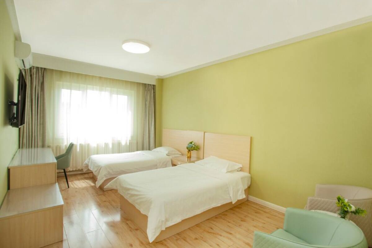 Una habitación de hotel con dos camas, un escritorio, una silla y un televisor.