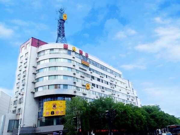 Un hotel de diverses plantes amb una façana corbada, nombrosos balcons i una antena destacada a la part superior.
