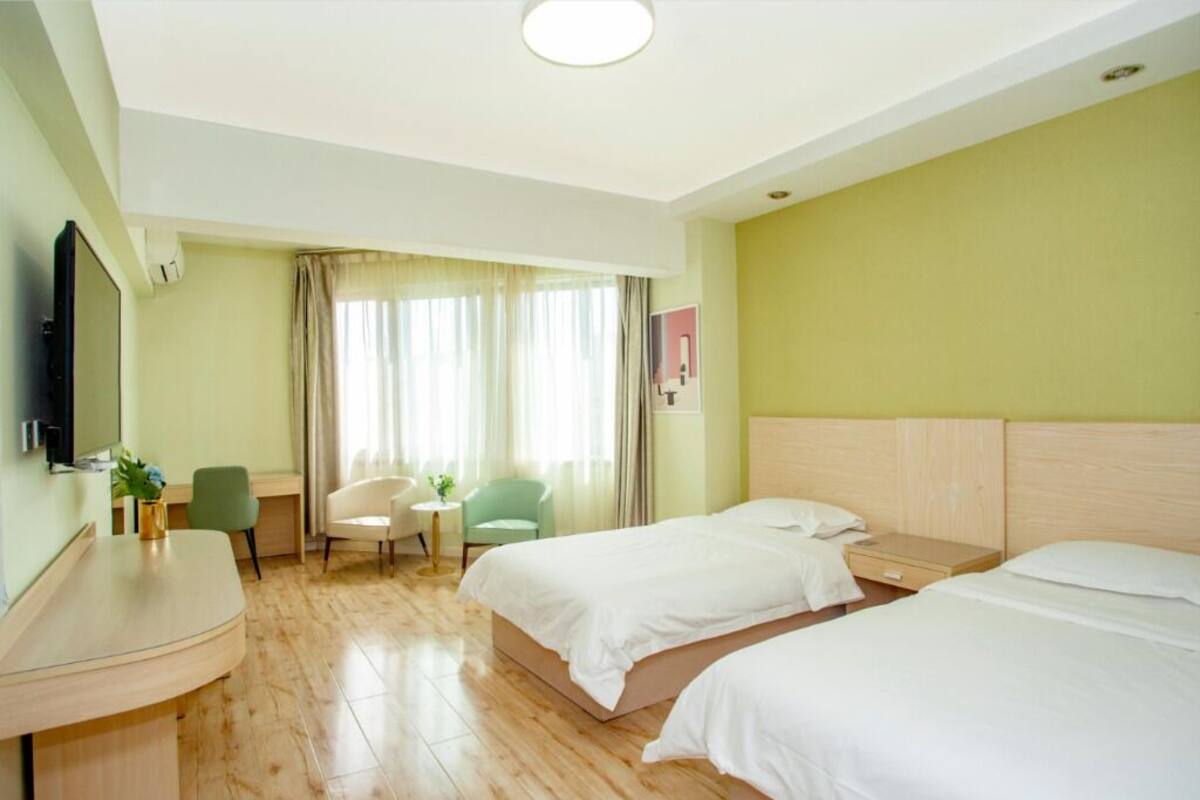 Una habitación de hotel con dos camas, un escritorio, una silla, una mesita y un televisor.