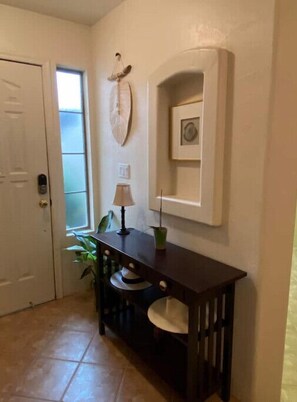 Stylish hallway with a console table, lamp, and potted plant, featuring a framed picture above.