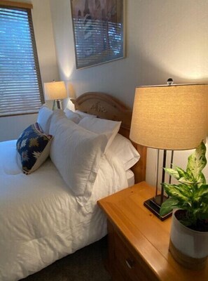 Restful retreat with a neatly made bed, a nightstand, and a potted plant.