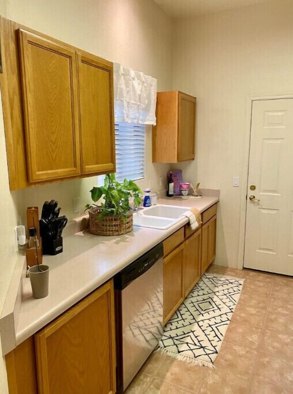 Kitchen with sink, window, and door, set against a patterned rug.