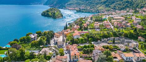A coastal town with a river, surrounded by mountains, featuring historic buildings and well-maintained gardens.