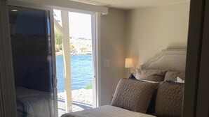 A bedroom with a bed, a nightstand, a lamp, and a view of the outdoors through a sliding door. - Margaritaville at River Lodge! Right on the river! (Parker Dam)