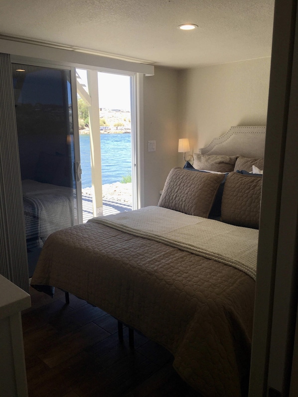 A bedroom with a bed, a nightstand, a lamp, and a view of the outdoors through a sliding door. - Margaritaville at River Lodge! Right on the river! (Parker Dam)