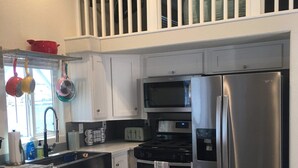 A modern kitchen with white cabinetry, stainless steel appliances, a wooden island, and a small seating area with stools. - Margaritaville at River Lodge! Right on the river! (Parker Dam)